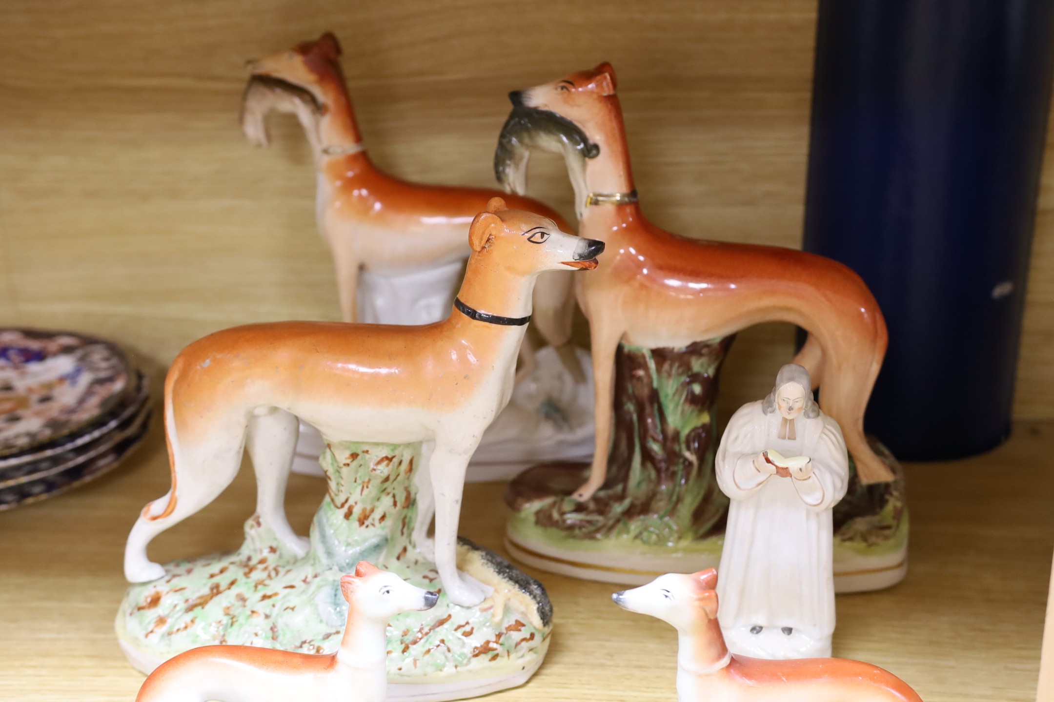 A Staffordshire pottery figure of John Wesley, six Staffordshire pottery models of hounds, and a white bisque group of two hounds on a cushion, tallest 29cm, (8)